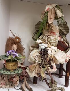 Handmade Country Dolls dressed in Vintage Linen Frocks seated on Antique French Rushed Seat Chair with Painted Copper Table and two Vintage Flowerpots) (40"W x 24"D x 34"H).  No portion of the proceeds for this lot will be donated to Alberta Ballet.