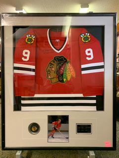 Framed Chicago Blackhawks Jersey Signed by Bobby Hull c/w Hockey Puck, Photograph, Plaque and Certificate of Authenticity. (# 307/607)