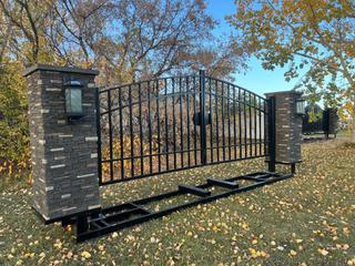 Unused Bulldog Industries 16 Ft. Entrance Gate, W/ Faux Stone Pillars, Solar Power Gate Opener, (4) Remote Controls, (2) Solar Power LED Pillar Lights W/Remotes, 16 Ft. Buried Frame.  **Note: Located off Site Near Innisfail, Contact Chris 587-340-9961.**