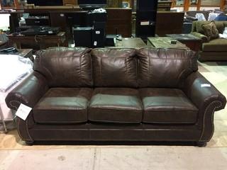 Benchcraft Leather-Look Upholstered Sofa with (2) Throw Pillows.